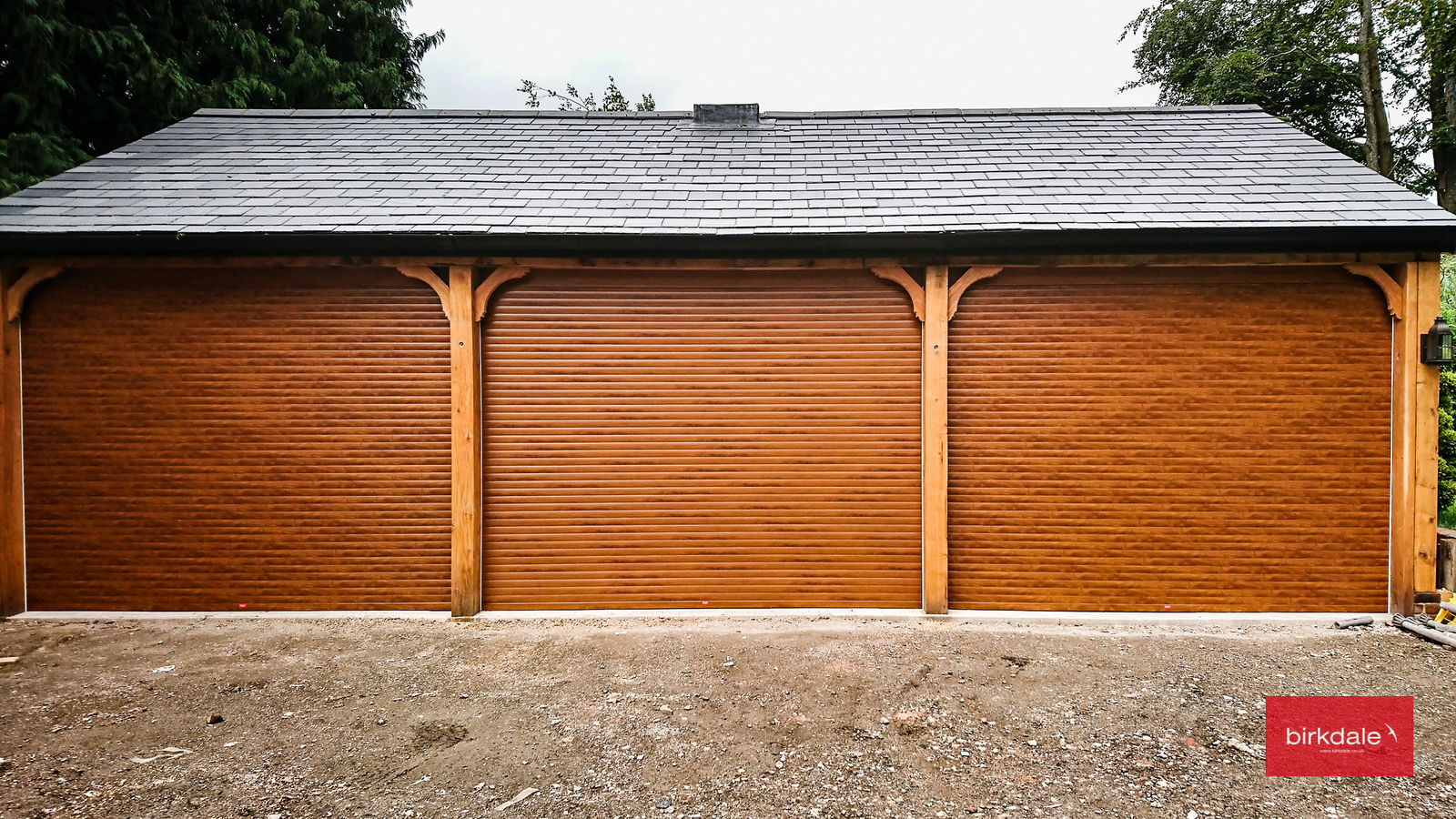 Cheap roller garage doors with a golden oak laminated finish fitted to a triple garage.
